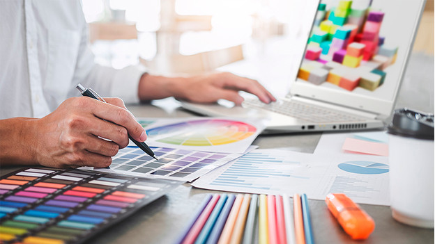 Man works on colorful design behind ConceptD laptop.