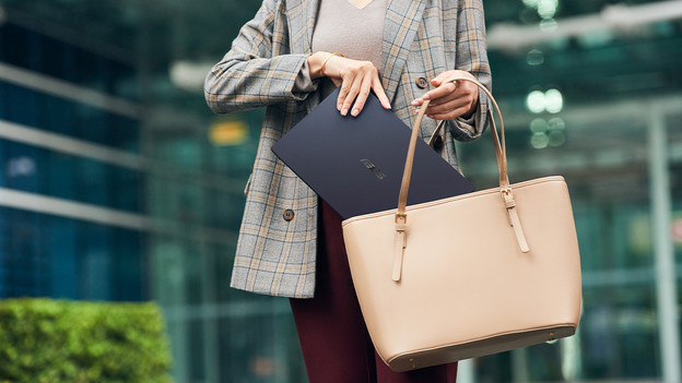 Vrouw die een kleine laptop in haar tas doet.