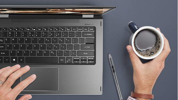 Man werkt met een hand op laptop en heeft in andere hand koffie. 