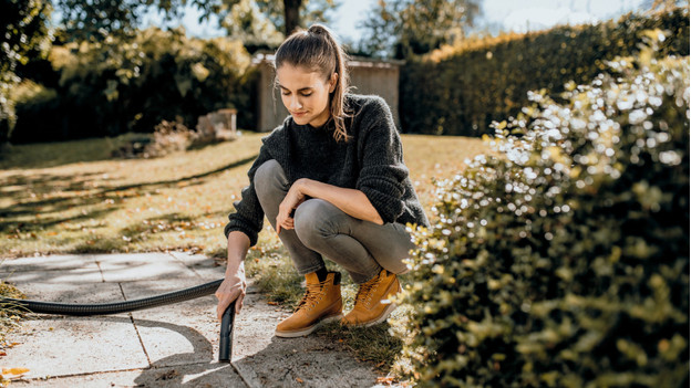 Vrouw gebruikt bouwstofzuiger in de tuin