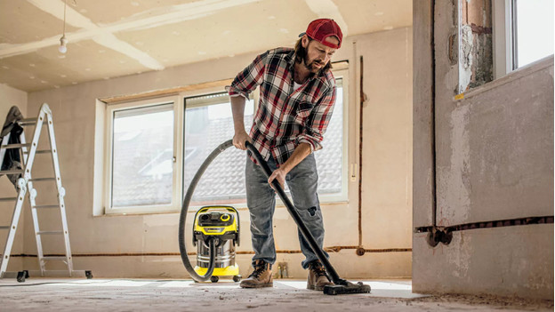 Person vacuums construction dust with construction vacuum