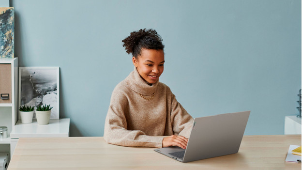 Vrouw die thuis op een laptop werkt.