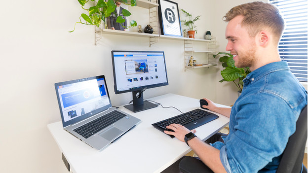 Specialist aan het werk met een monitor en laptop naast elkaar