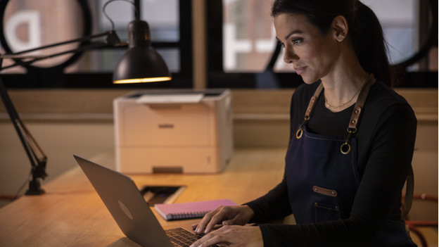 Person behind laptop with Brother printer