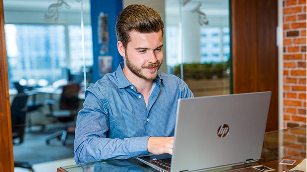 Jongen werkt achter HP laptop op kantoor. 