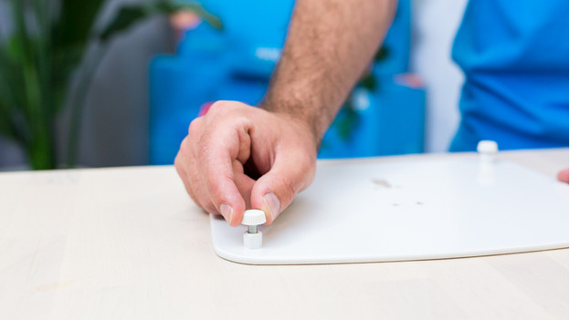 Iemand draait de voetjes op de vloerplaat van de BlueBuilt speakerstandaard