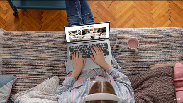 Someone sitting on the couch and working on a laptop.