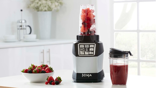 Ninja blender en blendbeker gevuld met rood fruit