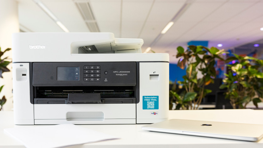 Brother printer on a table with laptop and paper