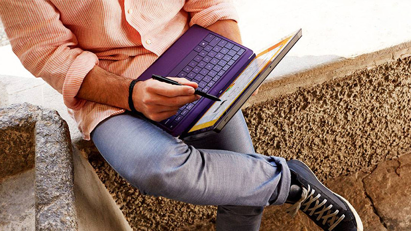 Man works with pen on 2-in-1 business laptop.