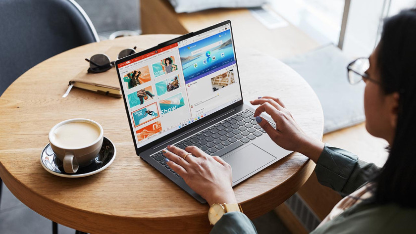 Person working on a Lenovo laptop in a cafe.