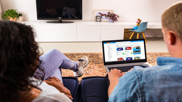 Couple on the couch looking for a Second Chance laptop on the Coolblue website