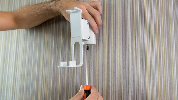 Iemand die de standaar van de BlueBuilt Muurbeugel vast schroeft