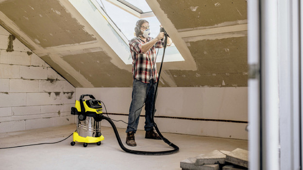 Person wearing a face mask uses a construction vacuum while sanding
