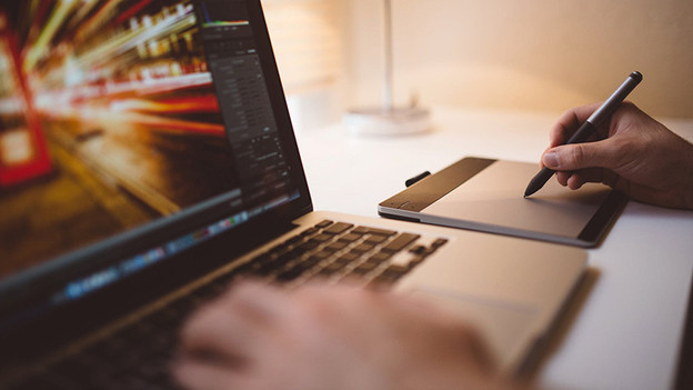 Persoon werkt met Adobe Photoshop via een tekentablet.