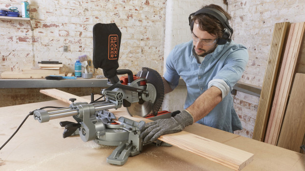 Man zaagt plank door met BLACK+DECKER afkortzaag