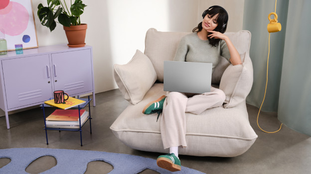 Vrouw werkt op 15 inch laptop met koffiekopje ernaast. 