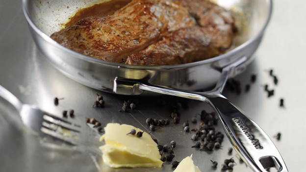 Stainless steel frying pan with steak and butter