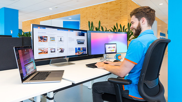 Man looks at 3 screens