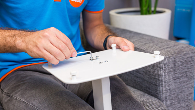 Iemand maakt de stang op de vloerplaat vast van de Bluebuilt speakerstandaard