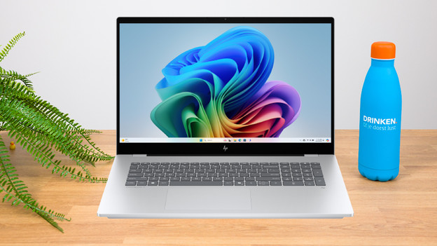 Vrouw werkt op 17 inch laptop met diverse accessoires op het bureau erbij. 