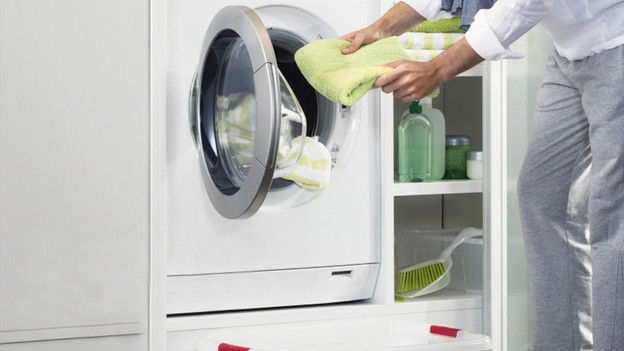 Person puts laundry into the washing machine.