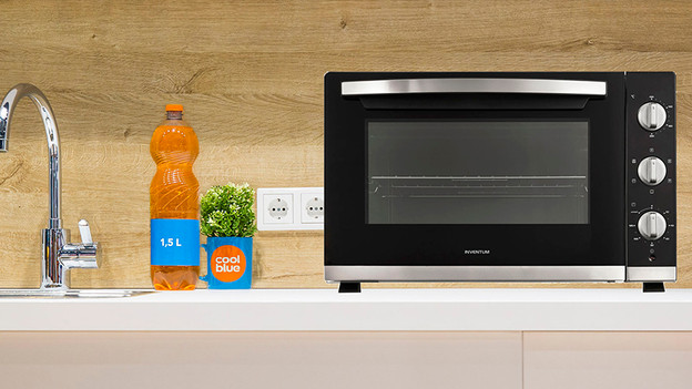 Mini oven met een fles ernaast op het aanrecht