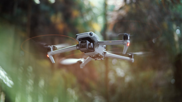 DJI drone hovers in place in the forest.