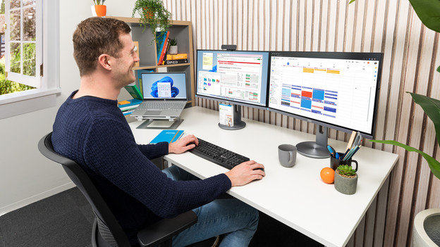 Man zit op een bureau stoel, op het bureau staan 2 monitoren