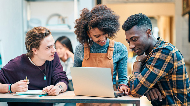 Drie scholieren werken samen achter laptop. 