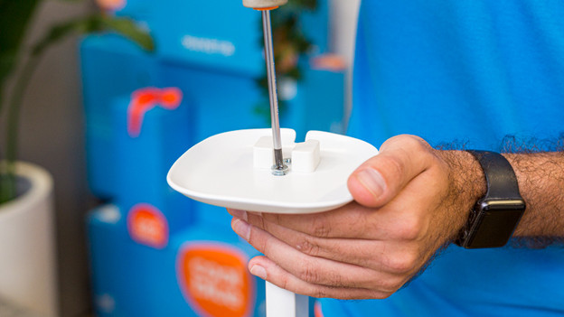 Iemand bevestigt de speakerhouder aan de Bluebuilt speakerstandaard